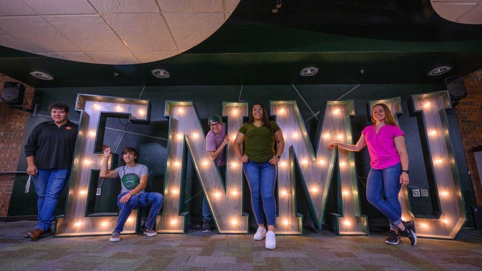 Group posing with lit ENMU letters indoors