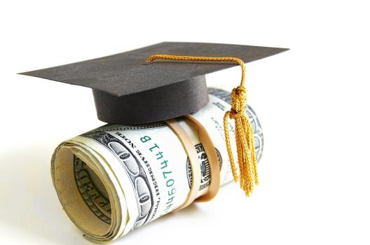 Graduation cap on rolled money symbolizing education costs