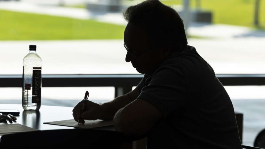 Silhouette of man writing at table with water bottle